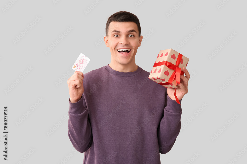 Poster Handsome man with gift card and present on white background