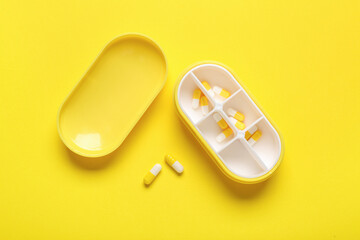 Container with pills on yellow background