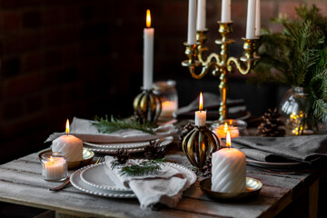 Rustic Scandinavian style zero waste eco-friendly dinner table decor for Christmas or new year family celebration. Wooden table, natural elements like pine cones, fir tree branches, candles
