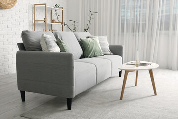 Interior of modern living room with grey sofa, table and shelf unit
