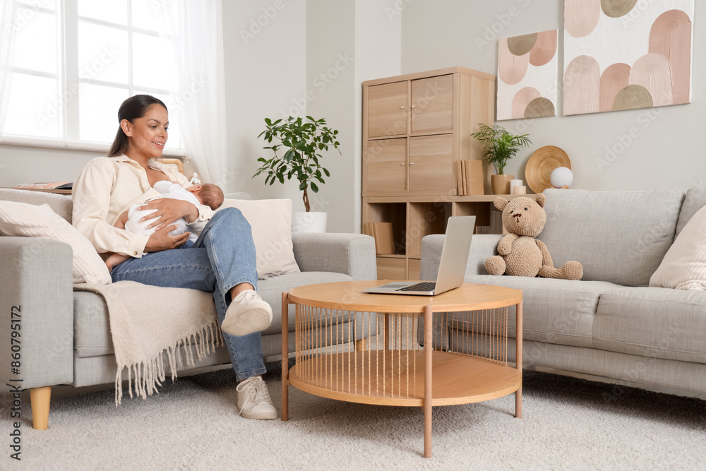 Poster Young woman breastfeeding her baby on sofa at home