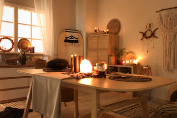Interior of witch's room with magic attributes, table and burning candles in evening