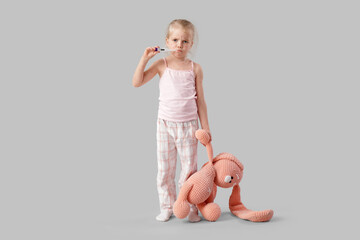 Sad little girl ill with chickenpox and toy measuring temperature on light background