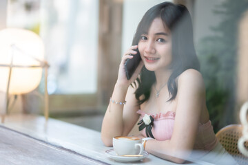 Portrait of beautiful happy Smiling asian woman relaxing and and smartphone sitting in cafe interior in coffee shop background,Business Lifestyle summer holiday concept