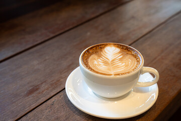 Hot coffee latte with latte art milk foam in cup mug on wood desk on top view. As breakfast In a coffee shop at the cafe,during business work concept,vintage style