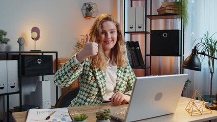 Like. Smiling Caucasian businesswoman looking approvingly at camera showing double thumbs up sign positive something good great news positive feedback. Happy girl using laptop at home office desk.