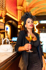 Woman standing in elegant dress holding cocktail in a bar