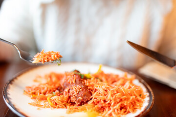 Enjoying a Hearty Meal of Spiced Rice and Meatballs