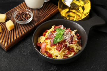 Frying pan with tasty pasta carbonara on black background