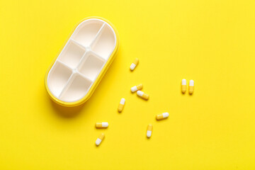 Container and pills on yellow background