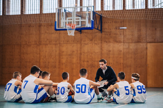 Circle of basketball players discussing tactics with coach