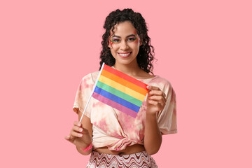 Young African-American woman with rainbow flag on pink background. LGBT concept