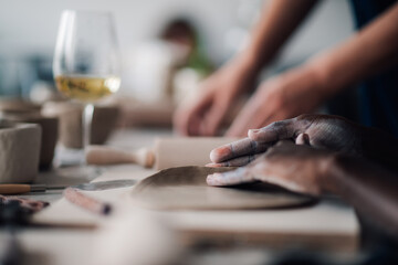 Close up of diverse attendee's hands making earthenware at pottery class