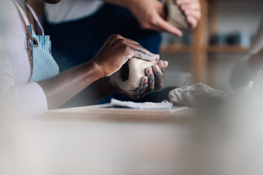Close up of diverse pottery class student's hands doing clay work.