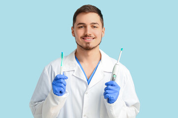 Fototapeta premium Male dentist with different toothbrushes on turquoise background