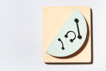 Composition with barbells for piercing and plaster podiums on grey background