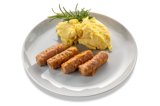 Pieces of sausage cooked in tomato sauce with mashed potatoes and rosemary branch in a plate isolated