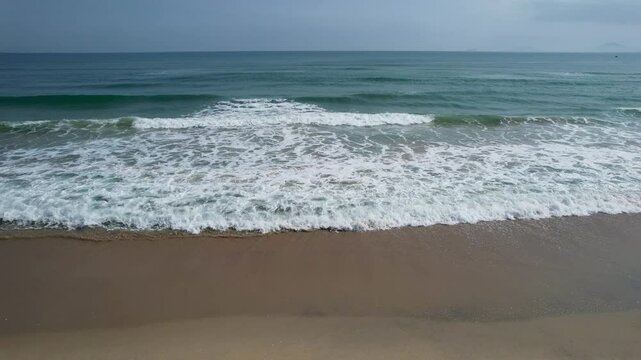 Tripod aerial footage of surf on An Bang Beach (South China Sea) on sunny day. Hoi An, Vietnam.