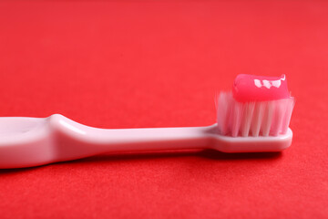 Pink toothbrush with paste on red background