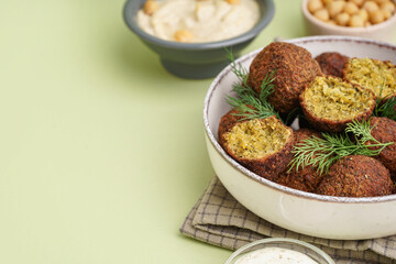 Bowl with delicious falafel balls and dill on green background, closeup