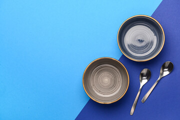Bowls with spoons on blue background
