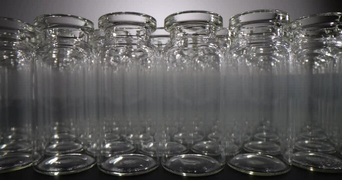 Large number of empty glass vials for vaccines stands in rows on table surface. Professional glassware for medical purposes and laboratory investigations