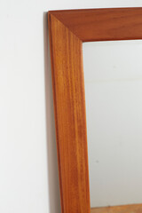 Vintage 60s wall mirror. Mid-century modern teak furniture. Interior close-up product photograph.