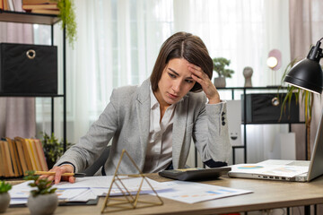 Depressed desperate businesswoman feeling worried about financial problem doing paperwork. Stressed...
