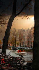 A canal boat sails on a Amsterdam canal in sunset