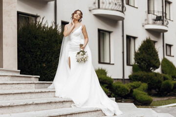 Fototapeta premium A woman in a white wedding dress is standing on a set of stairs