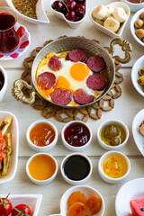 Fresh Traditional Turkish Breakfast on the wooden table with copper egg pan and white plates,vertical image