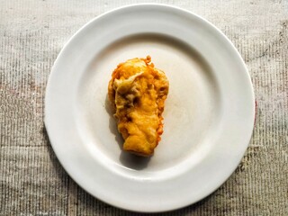 A fried banana on a white plate.