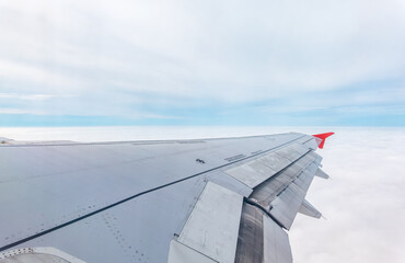 Fototapeta premium View from the airplane window at a beautiful cloudy sky and the airplane wing