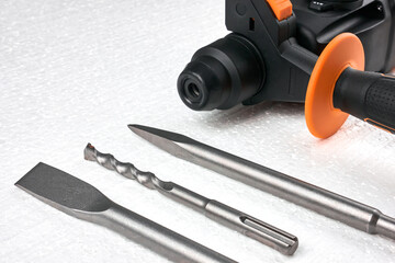 Hammer drill with drills on a white foam  panel, close-up. Power tool with drills and chisel. Construction works, rotary hammer