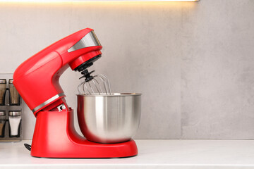 Modern red stand mixer on white countertop in kitchen, space for text