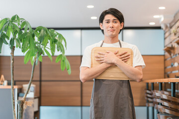 カスハラを受けて困る・悲しい表情のカフェの店員・ホール係の若いアジア人男性
