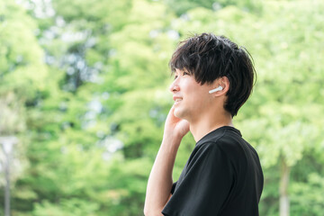 スポーツ・トレーニング中にワイヤレスイヤホンで音楽を聴く・ブルートゥースイヤホンを使う男性
