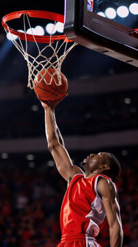 A basketball player is in mid-air, attempting to dunk the ball