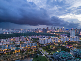 Obraz premium Ho Chi Minh City skyline evening storm during wet season with drone view of Saigon river, modern architecture and wetlands.