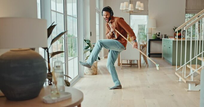 Happy, man and singing or dancing with broom while sweeping for fun cleaning, housework and chores. Excited, male person and housekeeping for hygiene with rhythm and silly moves in living room