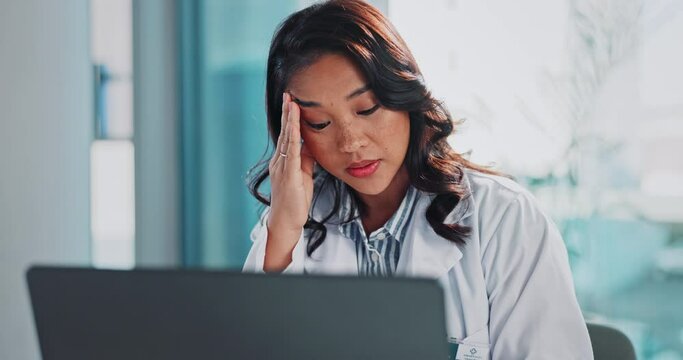 Asian woman, doctor and headache with laptop or stress in depression, anxiety or pressure at hospital. Female person or medical employee with migraine in fatigue, burnout or overworked at clinic