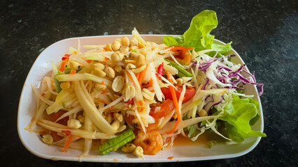 Thai papaya salad consists of papaya, roasted peanuts, chili, lime and tomatoes.