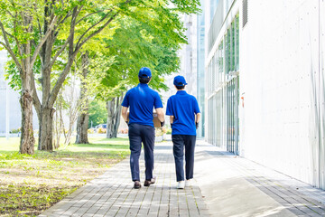 Rear view of delivery workers walking and carrying luggage in front of a building