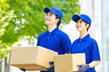 新緑を背景に荷物を持つ作業員