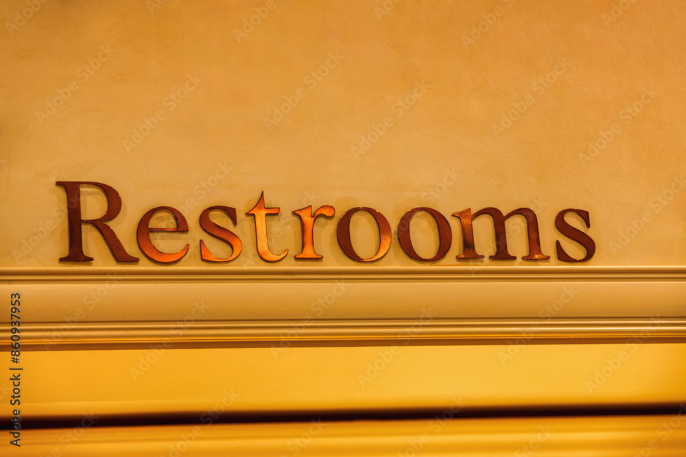 Wall mural restrooms sign on the wall, font text with golden letters