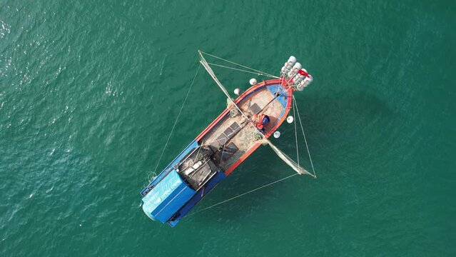 Rotating top view aerial footage of fishing boat in the sea on sunny day. Hoi An, Vietnam.