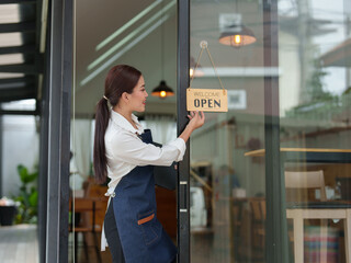 Starting a successful small business Small business owner SME Beauty Girl stands holding an open sign in front of a coffee shop. Coffee shop owner, female Asian barista, SME entrepreneur.