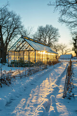Greenhouse on a farm field with snow during a winter sunrise