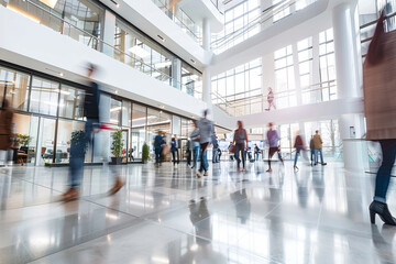 Fototapeta premium Bright business workplace with people walking in blurred motion in a modern office