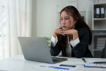 A businesswoman who is tired, stressed, and sore from working for a long time. After waiting for news Unsuccessful business approval results on laptop in office. Startup time concept, office syndrome